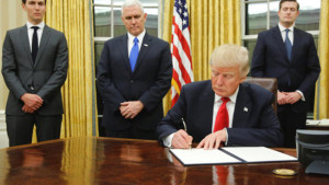 U.S. President Donald Trump, flanked by Senior Advisor Jared Kushner (standing, L-R), Vice President Mike Pence and Staff Secretary Rob Porter welcomes reporters into the Oval Office for him to sign his first executive orders at the White House in Washington, U.S. January 20, 2017. REUTERS/Jonathan Ernst TPX IMAGES OF THE DAY